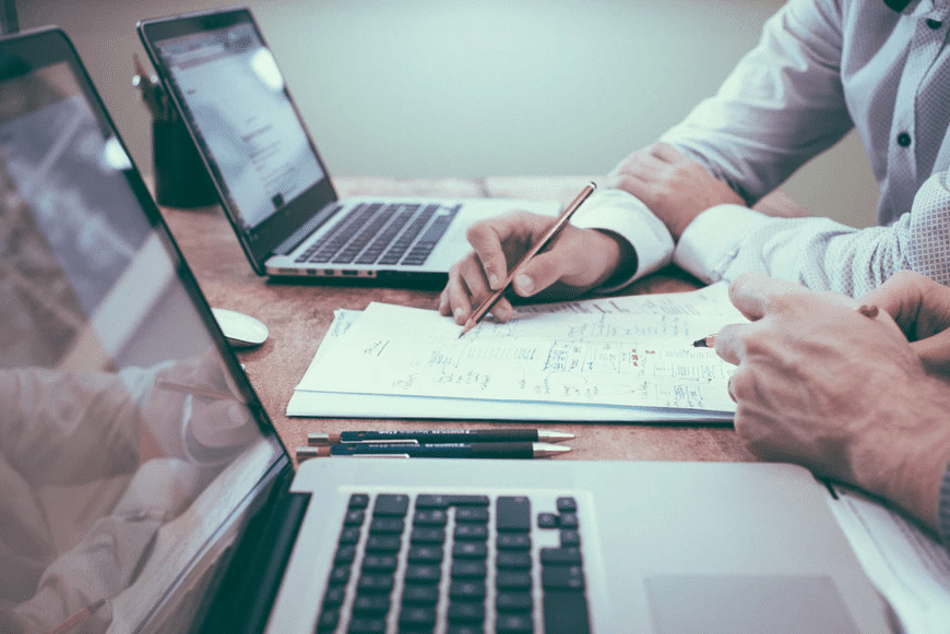 A person holding a pencil near a laptop